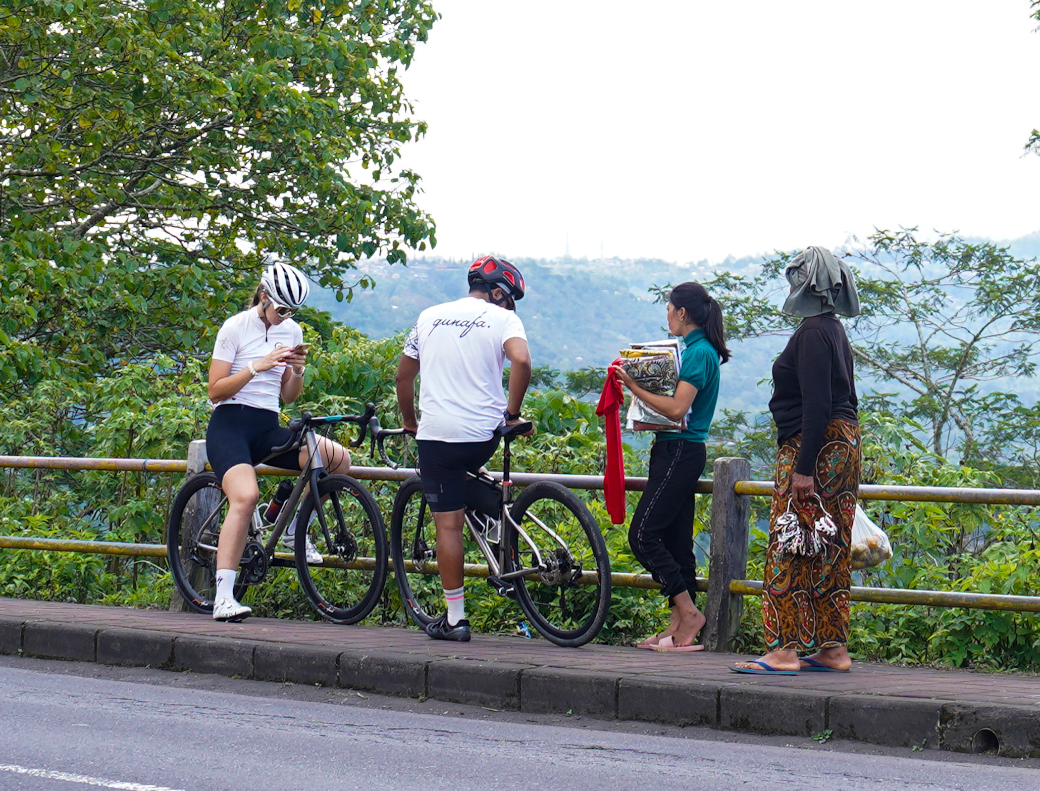 Qunafa cyclists on a road with a scenic background in Bali. By Qunafa Travel