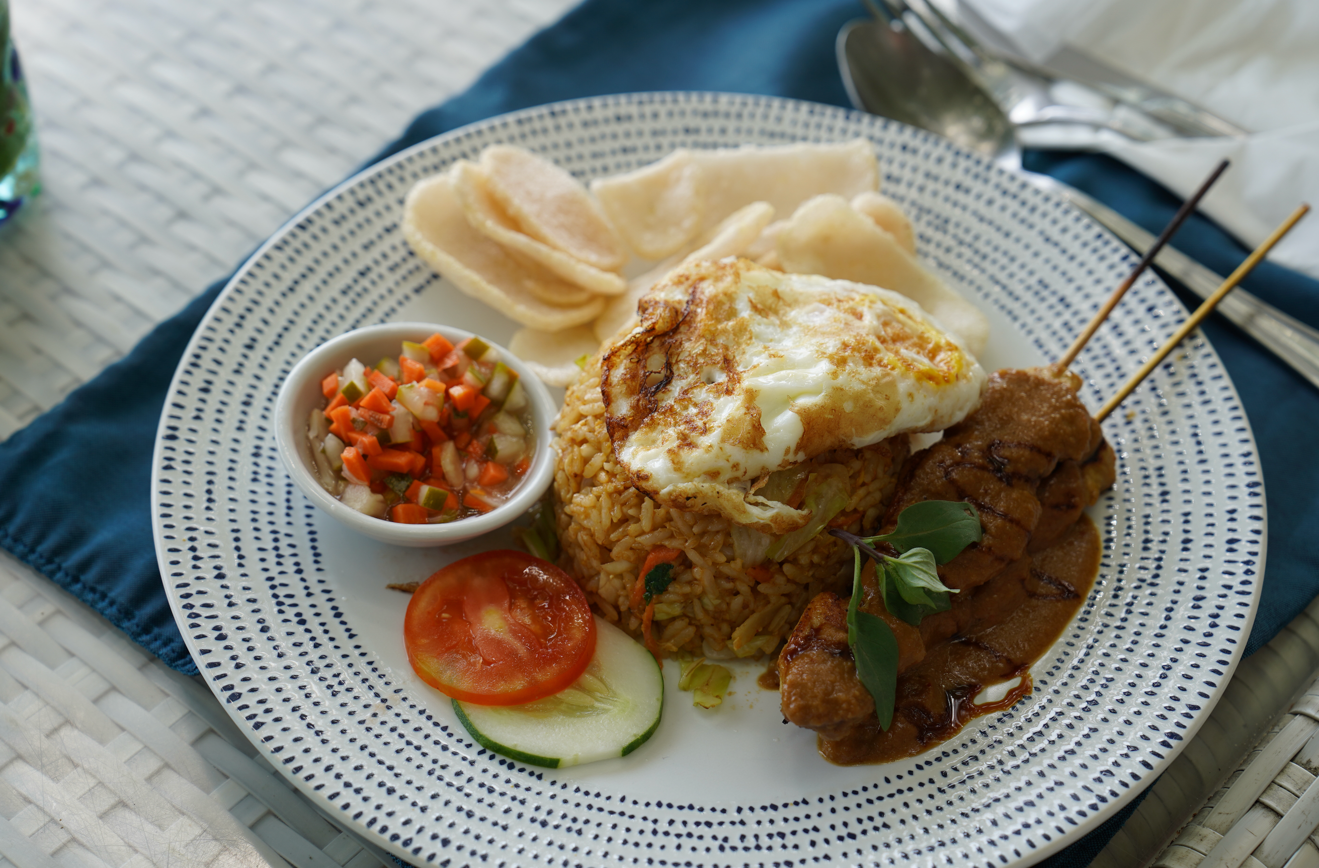 Qunafa travel: Plated meal with rice, fried egg, skewered meat, and vegetables on a white plate.