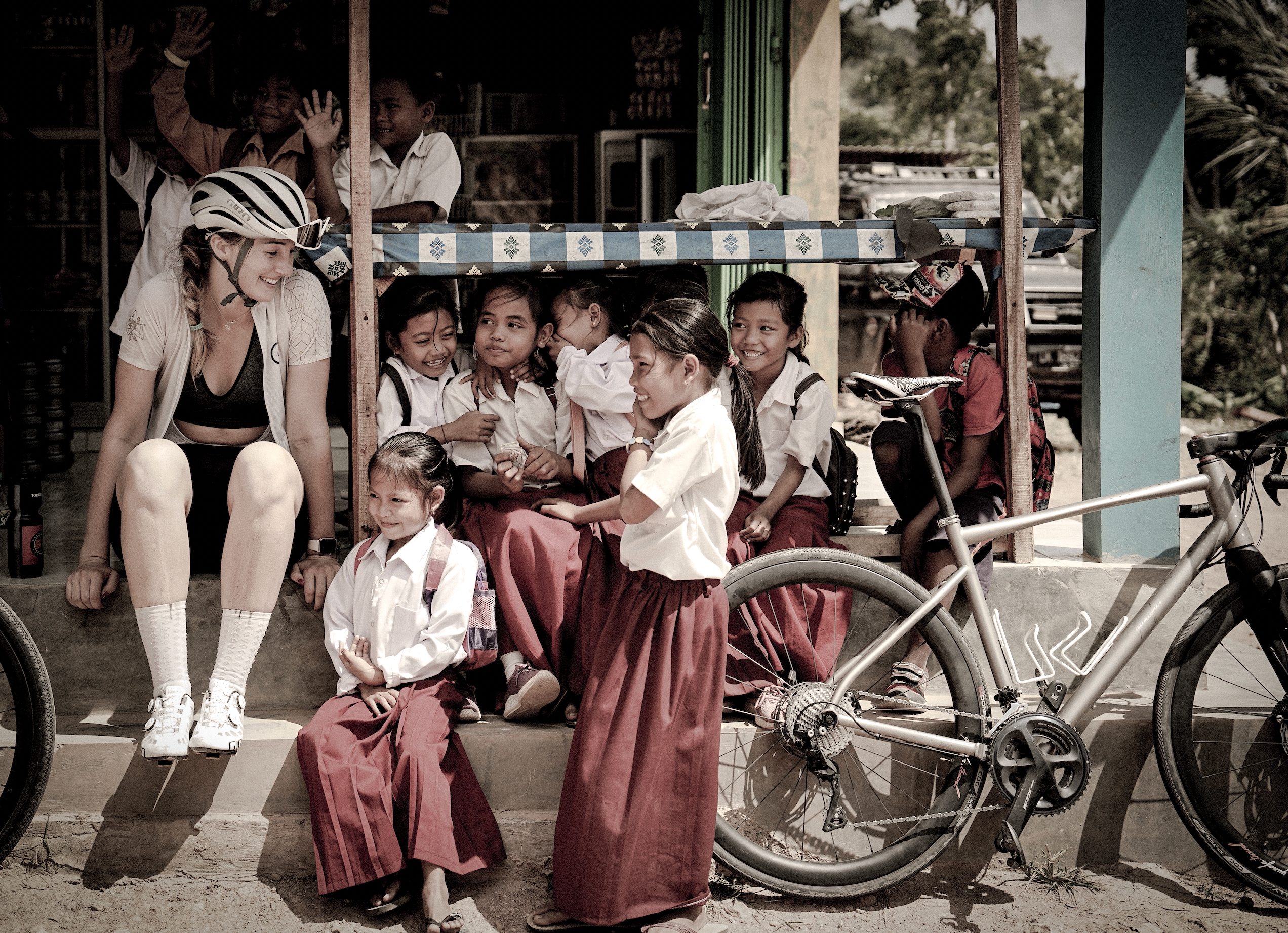 Laurel with a helmet interacting with children in front of a store with bicycles. Children out of curiosity. by Qunafa Travel