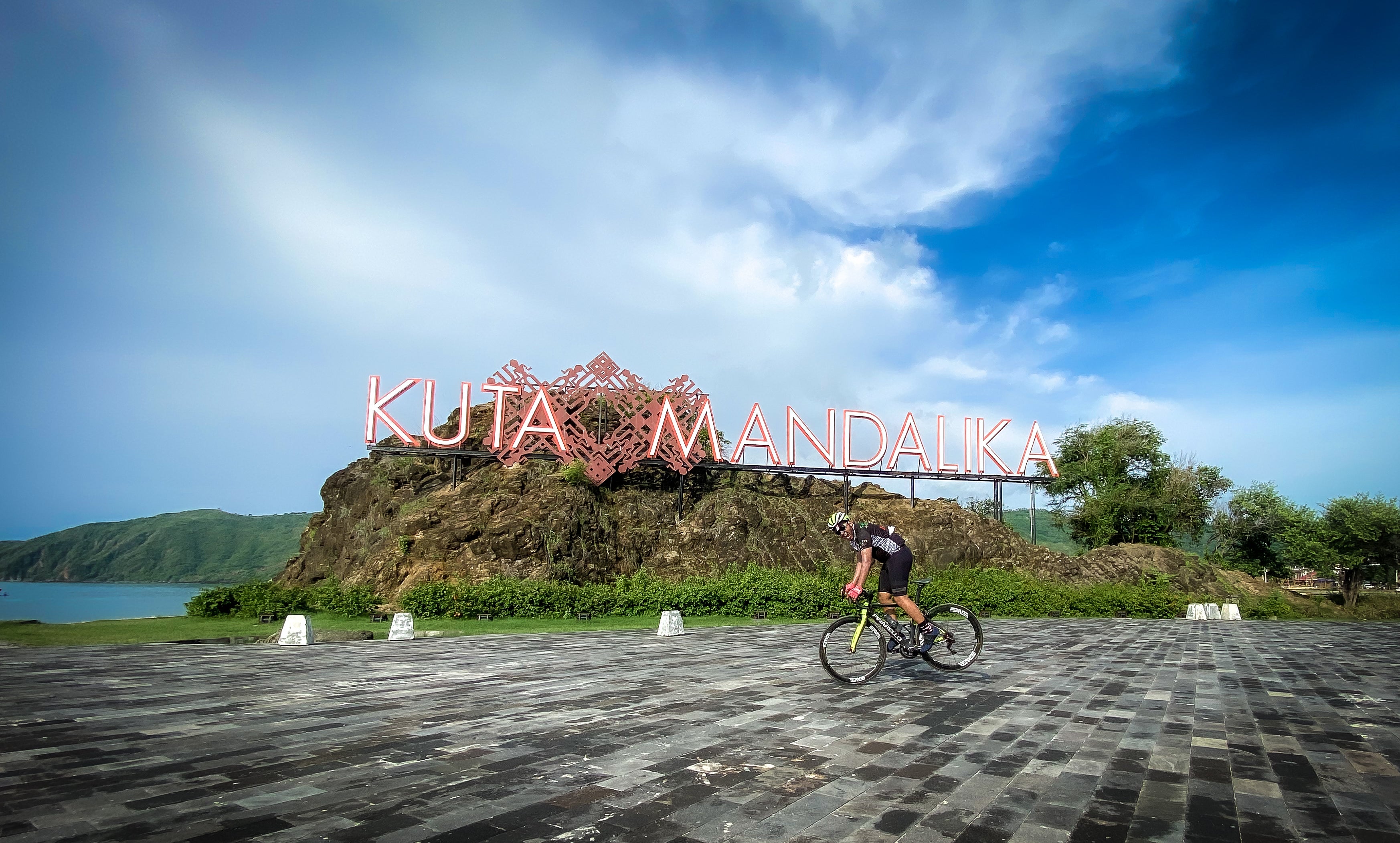 Cyclists riding along Lombok's coastal highway with turquoise water views — Qunafa Travel